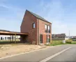 Huis in Maaseik moderne nieuwbouw met rode steen en zadeldak