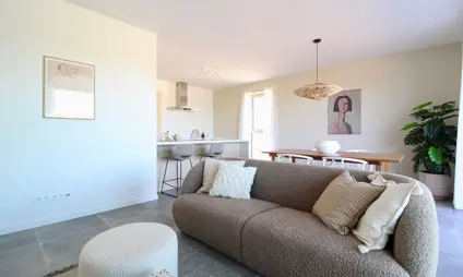 Geel Laar mooi interieur modern cementvloer living sofa zetel poef houten eettafel warme kleuren kunst schilderij